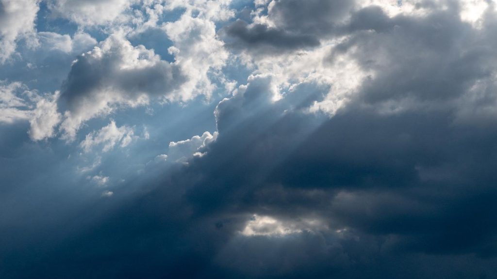 Sun light beams through clouds partially covering blue sky
